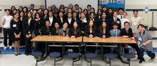 Students sitting and standing together behind table