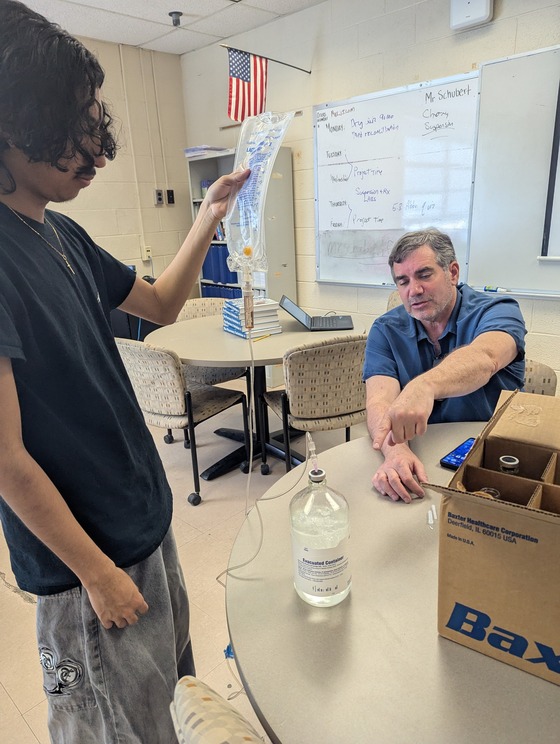 Student transferring IV fluid to container