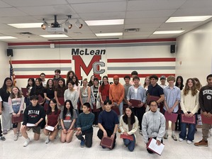 A group of young people standing in front of a wall with "McLean" signage, holding certificates.
