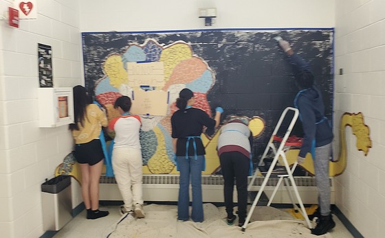 Students repainting a mural in the upstairs hallway