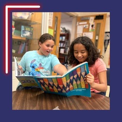 two students smile while looking through a Westlawn yearbook