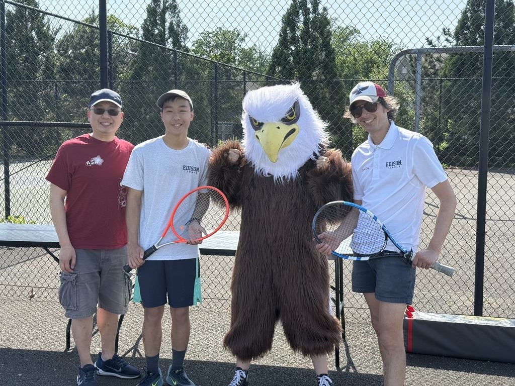 3 people standing with the eagle mascot holding tennis rackets
