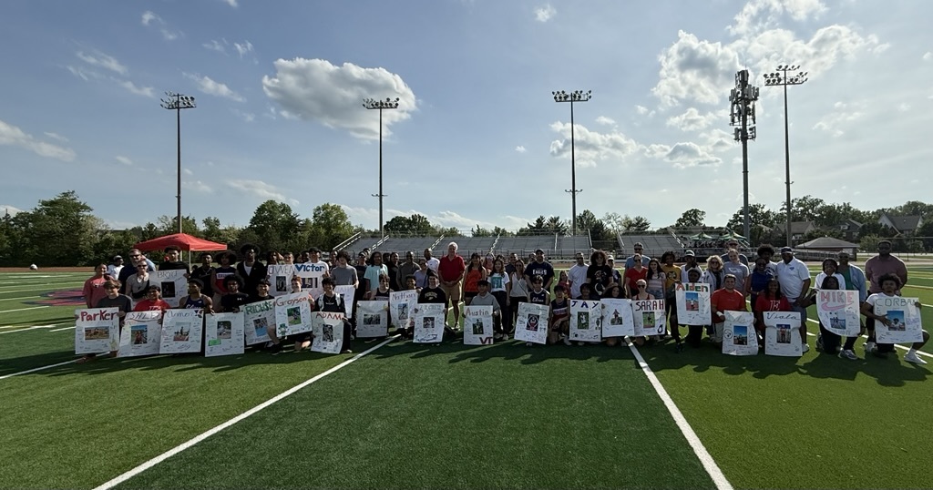 students on the field holding signs