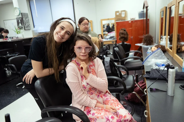 Cosmetology student standing beside seated student