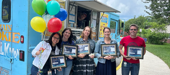 staff members smiling for a photo with their awards