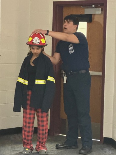 EMT student helps another put on gear