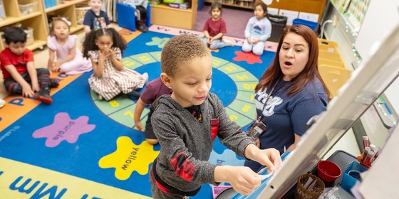 student writing on white board in kindergarten