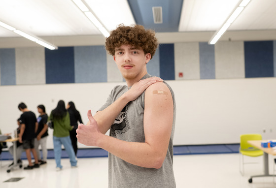 male student giving a thumbs up after receiving a vaccine