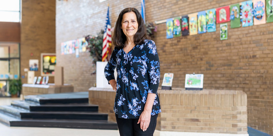 A teacher stands in a school vestibule