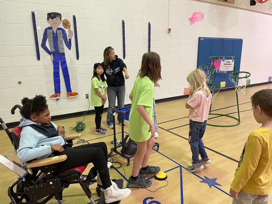 Students using sports equipment with help from friends