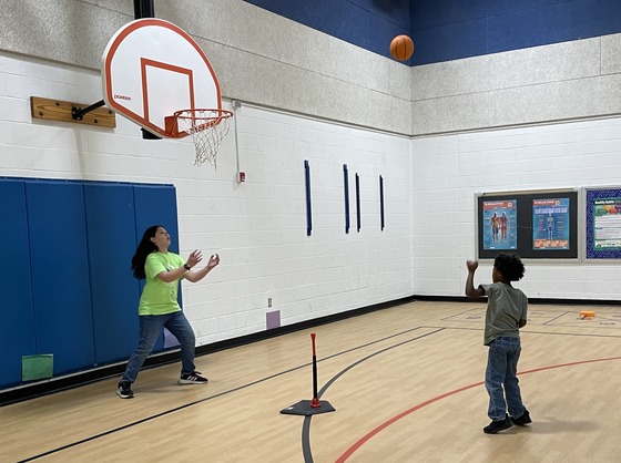 Students using sports equipment with help from friends