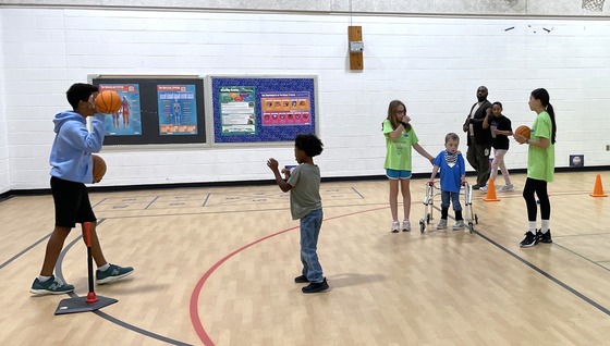 Students using sports equipment with help from friends