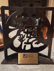 Metal plaque with cut-out hands design and engraved text on a metal plate.