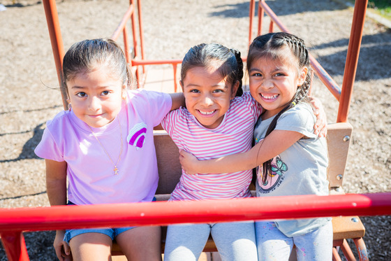 photo of three girls on playground equipment