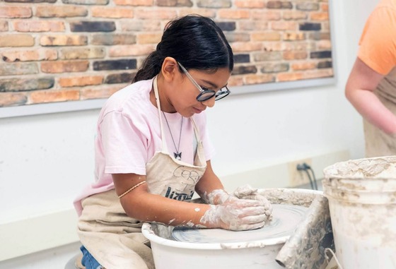 student doing pottery on a wheel