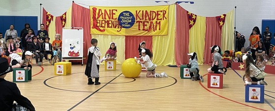 Kindergarten students dressed as dogs and a trainer performing tricks