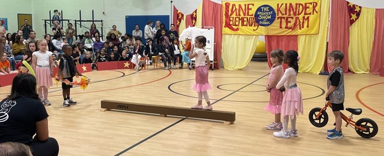 Kindergarten students performing "tightrope" tricks on a balance beam