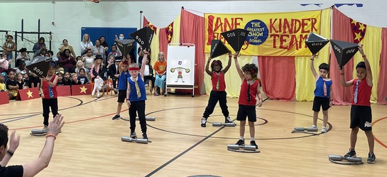 Kindergarten students dressed strong men performing tricks
