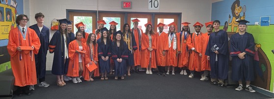 Class of 2025 graduates posing the main lobby of their old school