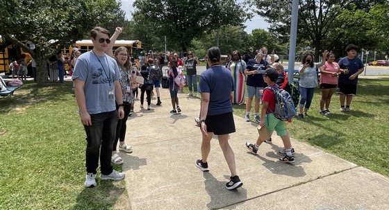 Staff members waving and clapping as students leave the building and head to the buses