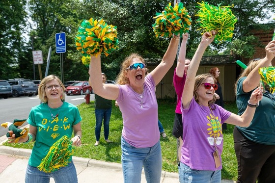 teachers cheering and waving goodbye to students on the last day of school