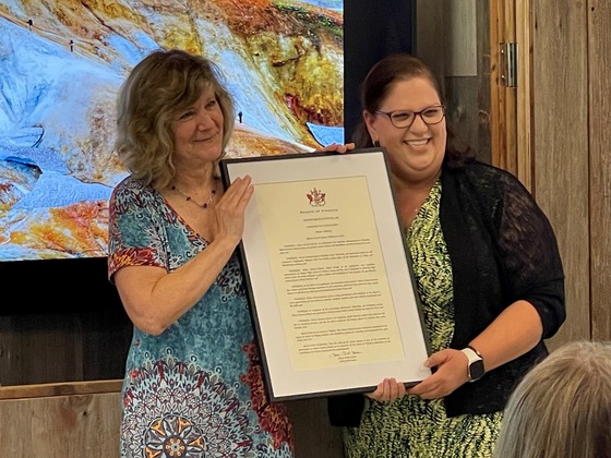 Two women standing together holding plaque