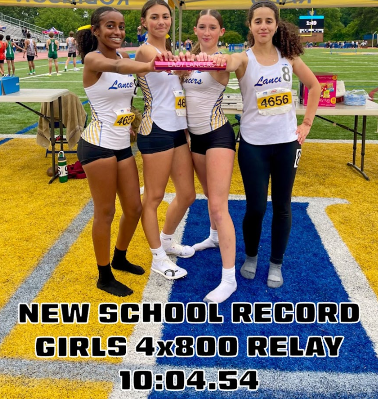 Girls Track and Field team members stand together holding baton