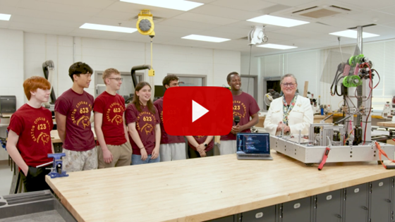 Students and Superintendent standing behind robot