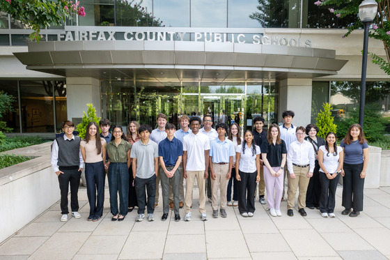 a group of about twenty college-aged interns smiling for a photo outside of FCPS headquarters