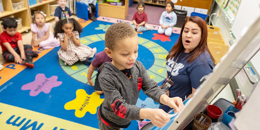 kindergarten students working on the whiteboard in front of class