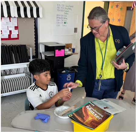 Superintendent Reid helps a science student studying matter and experimenting with slime