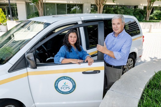 two employees smiling by their vehicle in front of Gatehouse