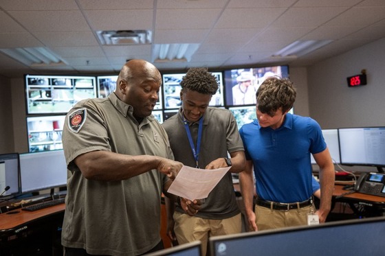 an employee shows student interns a piece of paper
