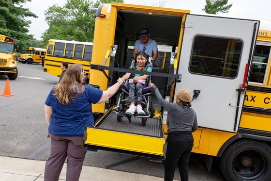 student gets out of a school bus using a chair lift