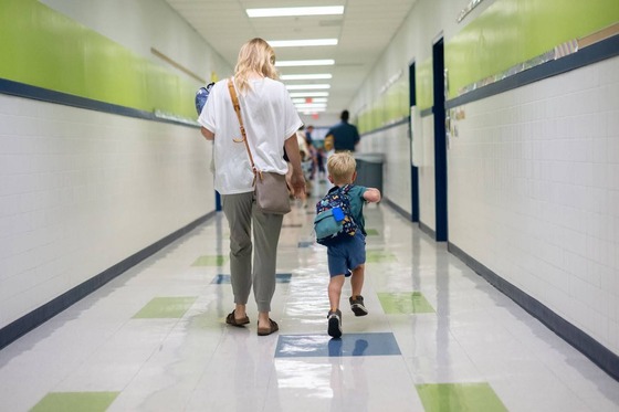 student and parent smile while walking down the hallway
