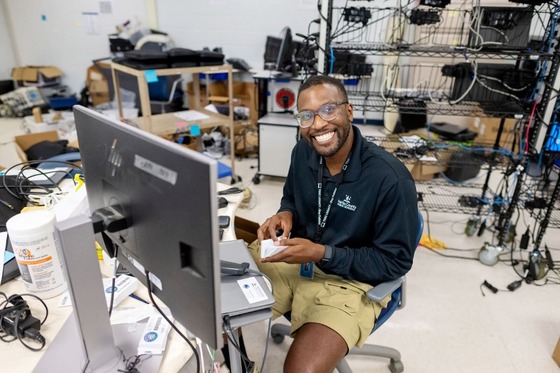 teacher smiling while untangling his laptop wires