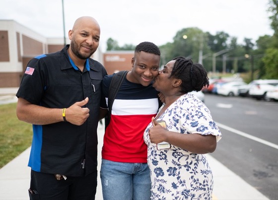 parents hug their high schooler on the first day of school