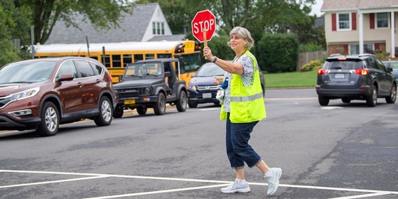 crossing guard on the street holding up a stop sign