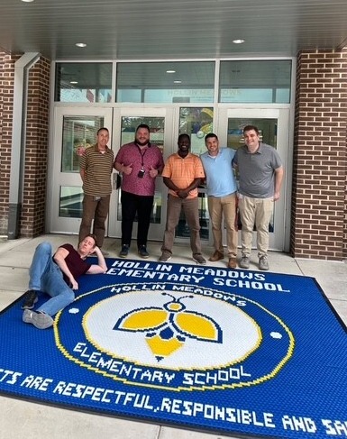 HMES Team members with a mat with the school seal.