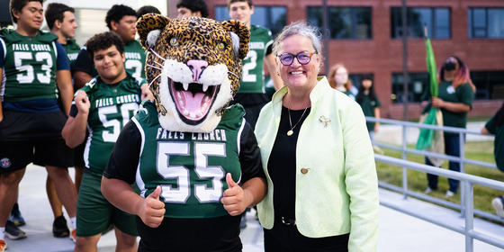 A student wearing a jaguar mascot head poses with Dr. Reid