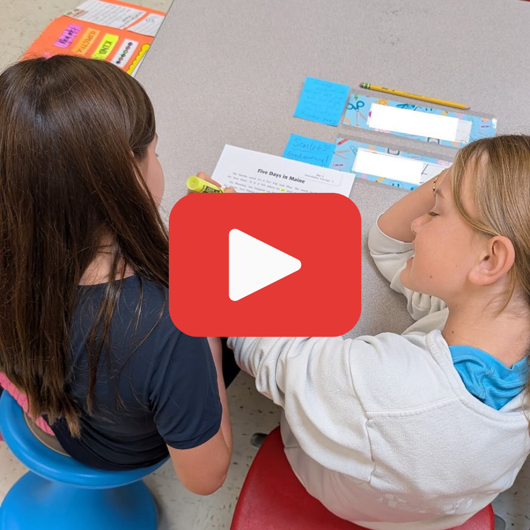 Two students sitting at a desk reading a passage and highlight words
