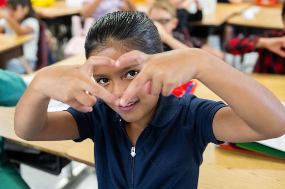 student makes a heart out of her hands