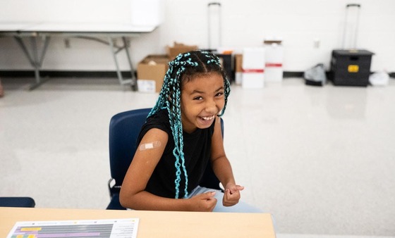 student smiles with a bandaid on her arm