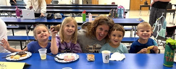 Teacher with several kindergarten students eating breakfast food
