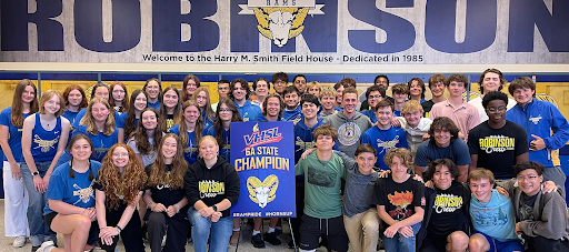 a group of students pose with a state championship banner