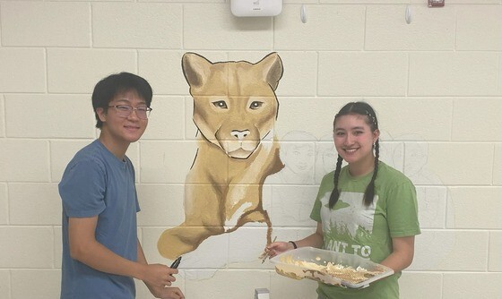 2 TJHSST students painting a mural of a cougar at Haycock ES