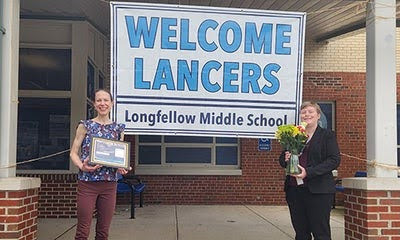 teacher smiles with award