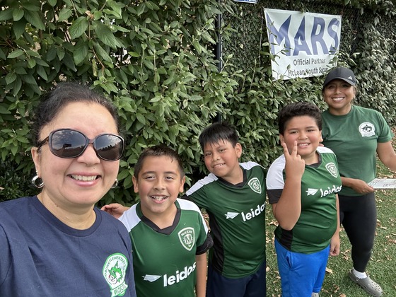 Ms. Iyer smiles with a group of boys from the soccer team 