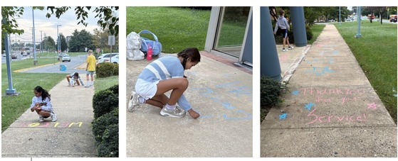 Student ambassadors drawing pictures and writing welcome messages with chalk in front of the school