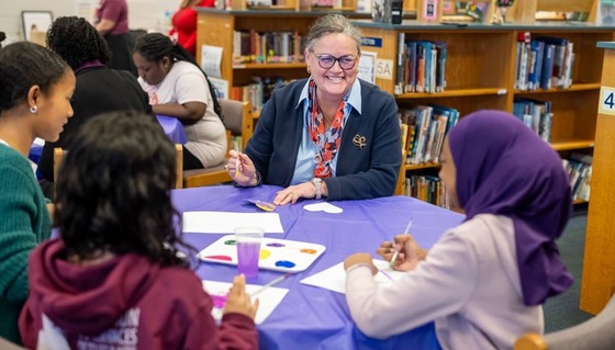Dr. Read sits at a table and crafts with students
